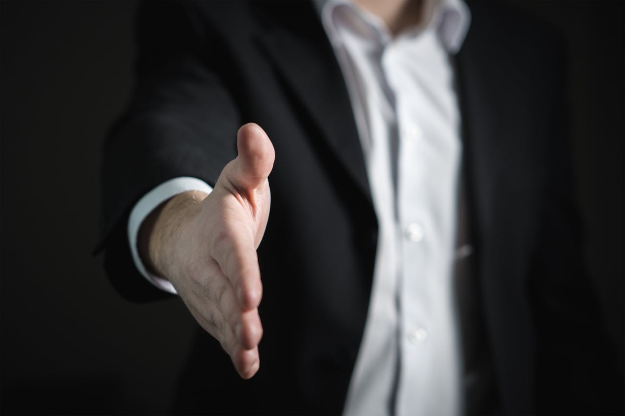 services-02 Close-up of a businessman extending hand for a handshake, symbolizing agreement and partnership.